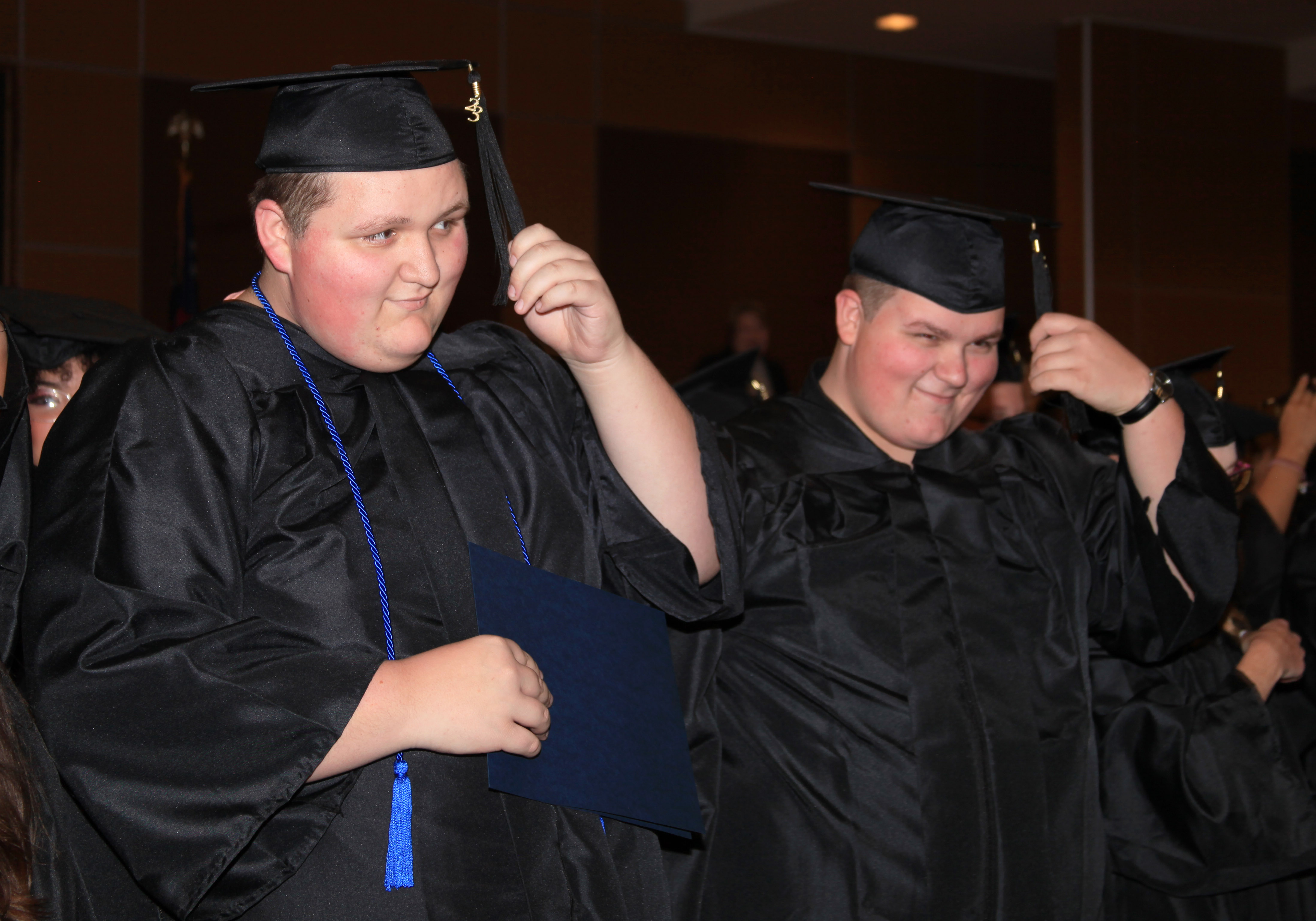 Christopher Shaw (left) and Aron Shaw move their tassels to celebrate graduating from GNTC’s Adult Education program with their GED® diplomas.