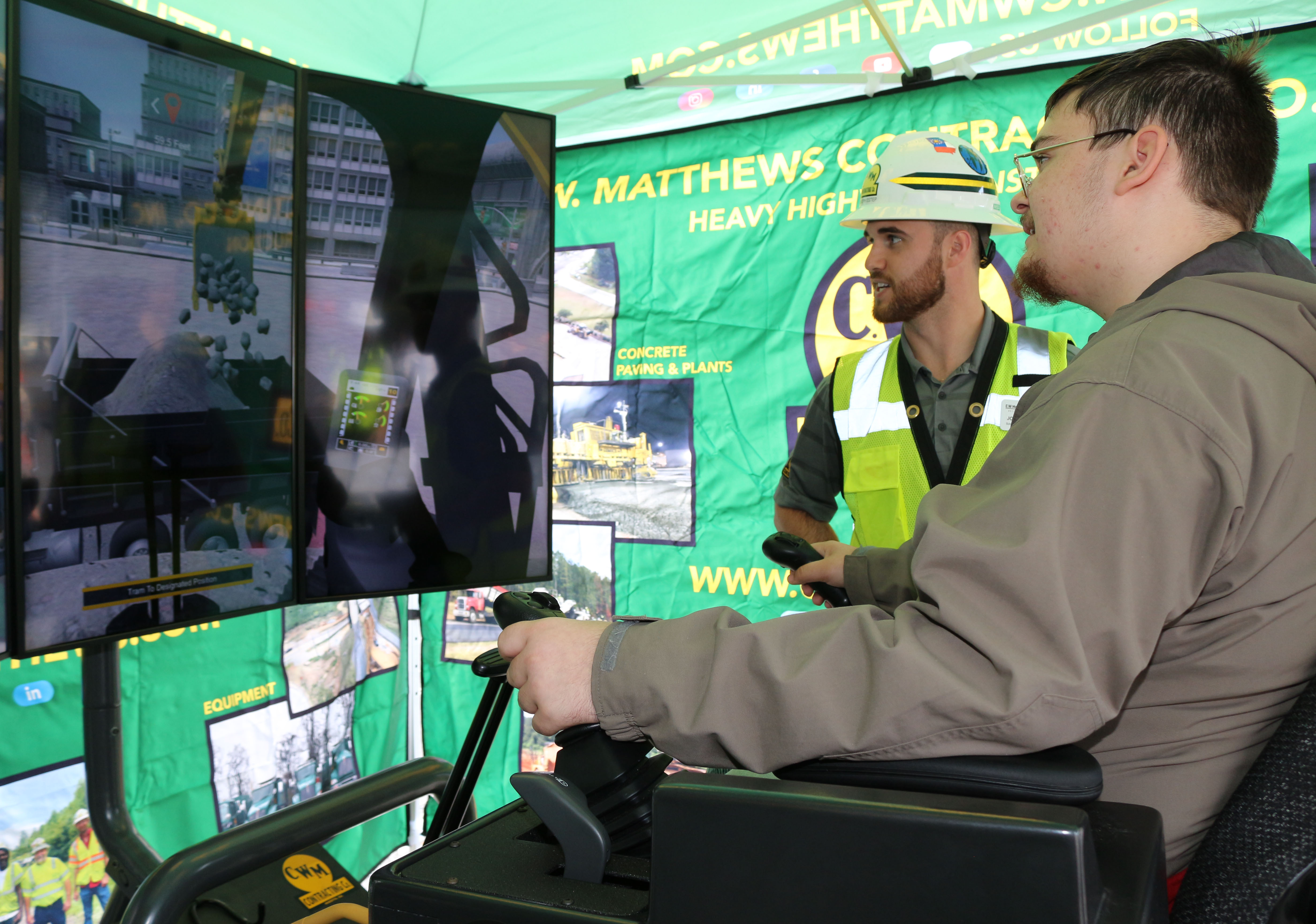 (From left) Joseph Estep, school recruiting specialist with C.W. Matthews Contracting Co. Inc. coaches Andrew Wheeler, a junior at Sonoraville High School (right), on the CAT excavator operator simulator.