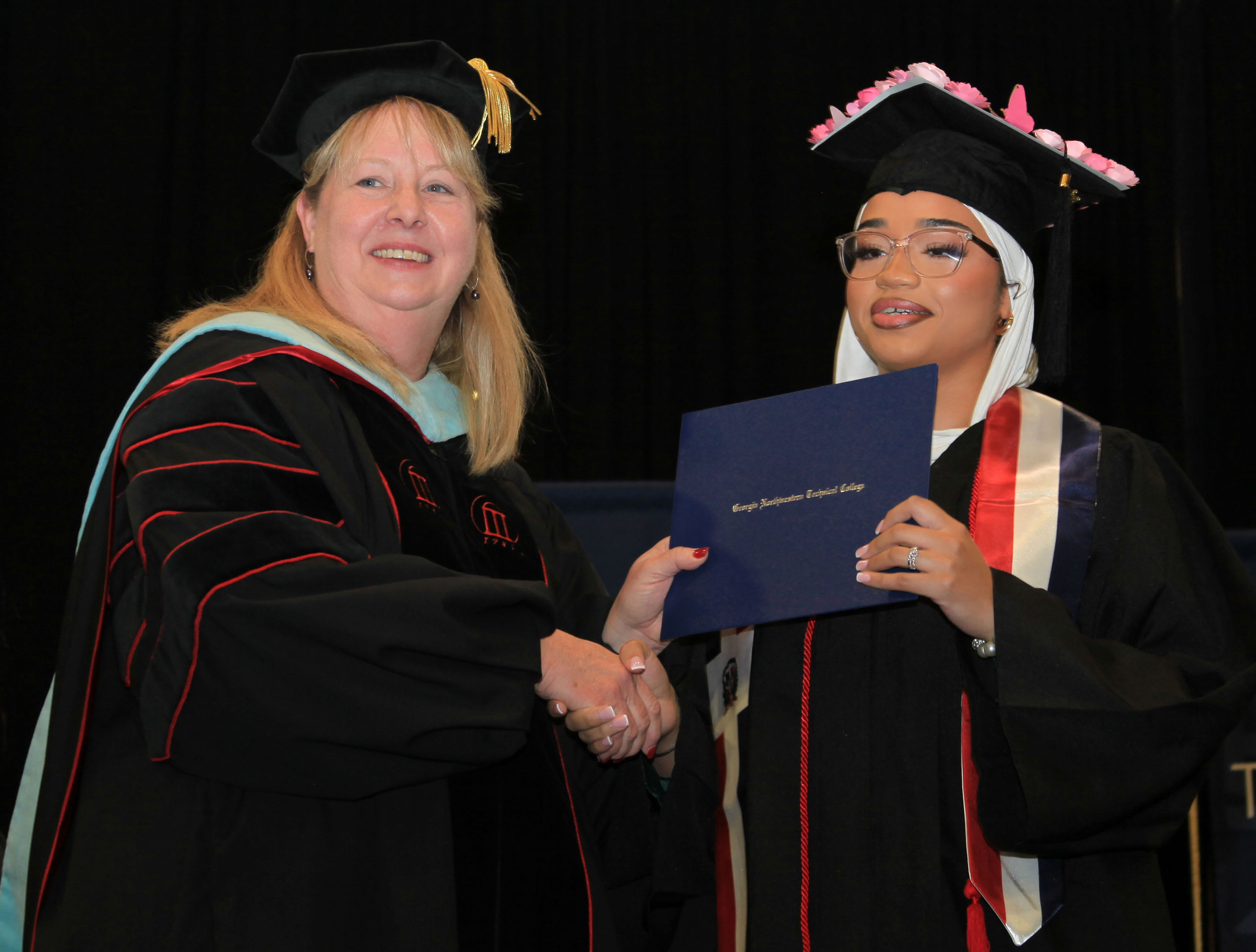 Dr. Heidi Popham, GNTC president (left), presents Luisa Maria Almonte Deleon with her diploma in Medical Assisting.